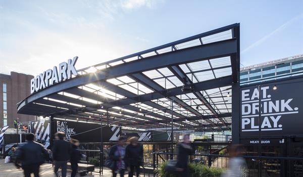 cantilevered metal canopy with Boxpark signage and Eat Drink Play signage, located outside with lots of pedestrians