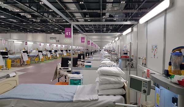 inside an NHS Nightingale Field Hospital set up inside a convention centre, showing rows of hospital beds and equipment bays